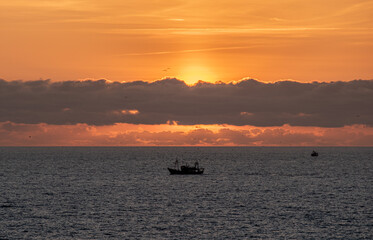 Naklejka na ściany i meble Sunset over the sea with fishing boat near Essaouira