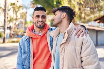 Two man couple hugging each other standing at park