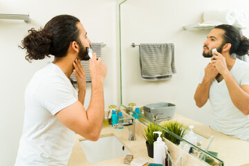 Mexican man using a trimmer and trimming his beard