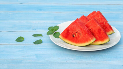 Red watermelon on a blue wooden table.