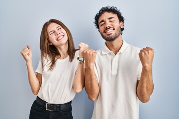 Young couple wearing casual clothes standing together celebrating surprised and amazed for success...