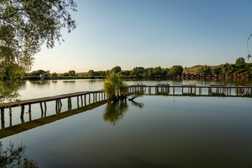 Fototapeta premium Wooden jetty over a lake under a blue sky in summer.