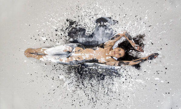 sexy naked woman in black and white color painted, lying decorative on the white, black, gray Studio floor. Creative, abstract expressive body art and painting