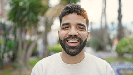 Young hispanic man smiling confident standing at park