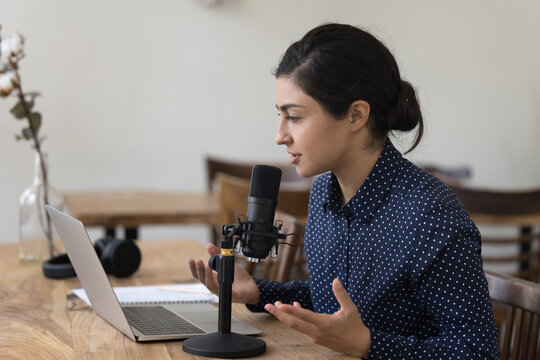 Indian teacher woman use laptop, professional microphone, give webinar, make speech, lead on-line lecture, record podcast, share skills, hold online class for subscribers, teach audience. Livestream
