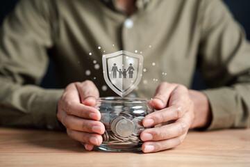 Businessman saving money coins accounting in jar for protect family and insurance concept. Protected from emergency by insurance and assurance health care life.