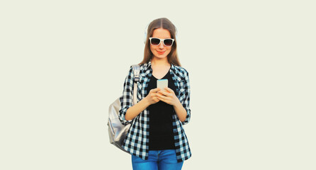 Portrait of teenager girl listening to music in headphones with phone on white background