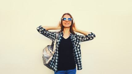 Portrait of happy smiling young woman in wireless headphones listening to music on white background