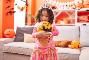 African american girl wearing princess costume holding pumpkin basket at home
