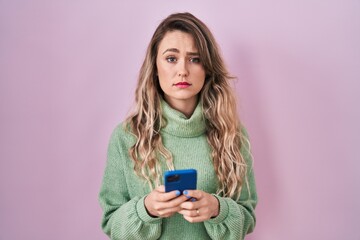 Young caucasian woman using smartphone typing message skeptic and nervous, frowning upset because of problem. negative person.