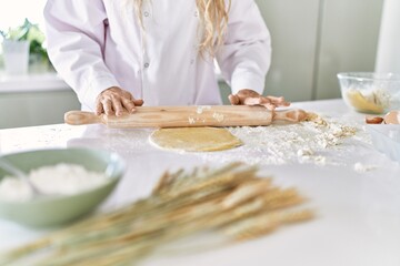 Obraz na płótnie Canvas Young woman wearing cook uniform kneading pasta dough at kitchen