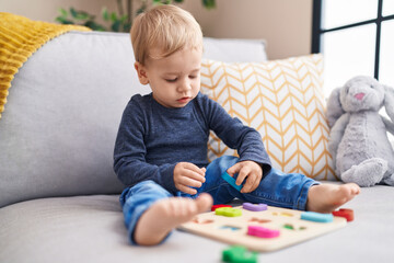 Obraz na płótnie Canvas Adorable blond toddler playing with maths game sitting on sofa at home