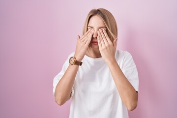 Young caucasian woman standing over pink background rubbing eyes for fatigue and headache, sleepy and tired expression. vision problem