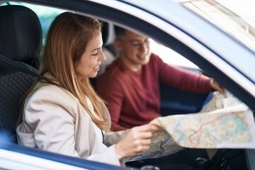 Man and woman mother and son looking city map sitting on car at street