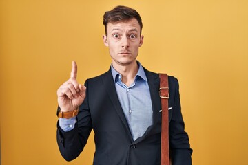 Caucasian business man over yellow background pointing up looking sad and upset, indicating direction with fingers, unhappy and depressed.