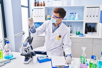 Young man scientist wearing medical mask working at laboratory