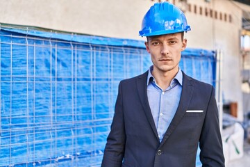 Young man architect standing with relaxed expression at street