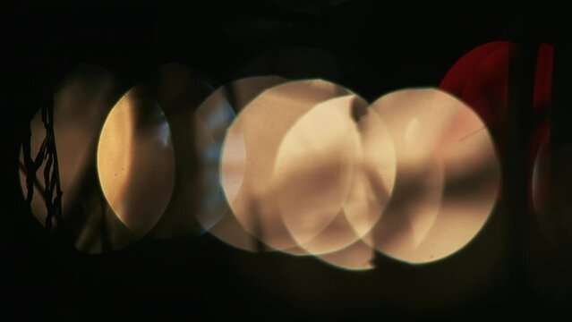Oncoming Cars' headlights as large bokeh-balls at night with silhouette of branches in front