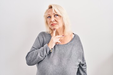 Middle age caucasian woman standing over white background thinking concentrated about doubt with...