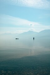 Fototapeta na wymiar Vertical shot of a Kootenay Lake with crystal clear water and mountains in the background, BC Canada