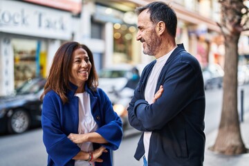 Middle age man and woman couple standing with arms crossed gesture at street