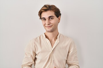 Obraz premium Young man standing over isolated background with hands together and crossed fingers smiling relaxed and cheerful. success and optimistic