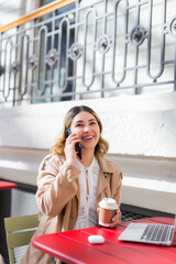 Happy woman talking on the phone in a coffee shop