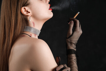 Beautiful young woman with love bites on her neck smoking cigarette against dark background, closeup