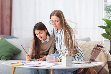 Drawing teacher giving private art lesson to little girl at home