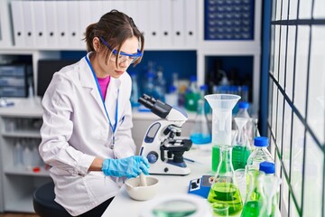 Fototapeta premium Young beautiful hispanic woman scientist mixing sample on bowl at laboratory