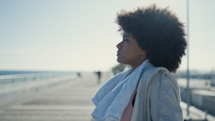 African american woman wearing sportswear leaning on balustrade at seaside