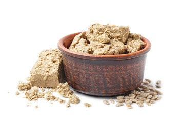 Bowl with pieces of halva and sunflower seeds on white background