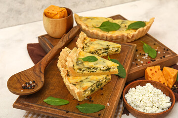 Board with pieces of delicious quiche on white table