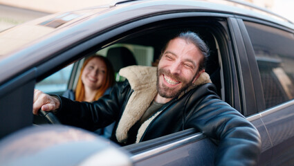 Man and woman couple smiling confident driving car at street