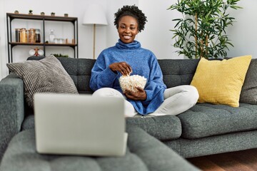 African american woman watching movie sitting on sofa at home