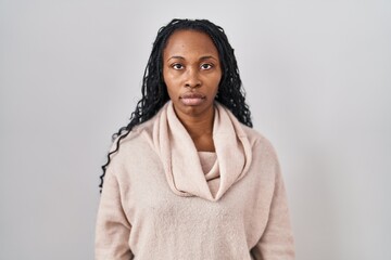 African woman standing over white background relaxed with serious expression on face. simple and natural looking at the camera.