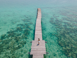 Female traveler walk lonely at long wooden bridge in the sea to sightseeing at landmark