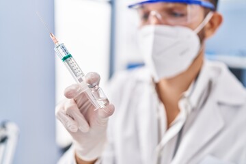 Young hispanic man scientist wearing medical mask holding covid vaccine at laboratory