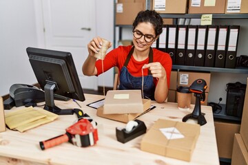 Young latin woman ecommerce business worker prepare package order at office