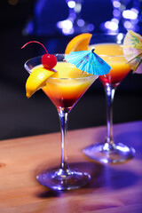 Glasses of tasty Tequila Sunrise with umbrellas on table in bar