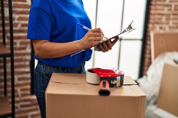 Middle age woman moving worker writing on checklist at new home