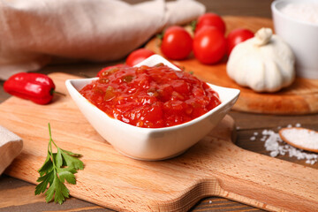 Board with bowl of delicious salsa sauce on wooden table, closeup