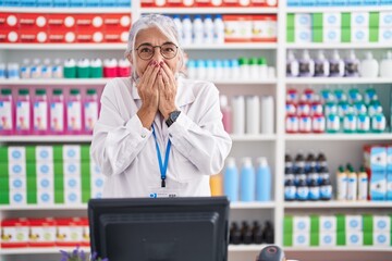 Middle age woman with tattoos working at pharmacy drugstore laughing and embarrassed giggle...