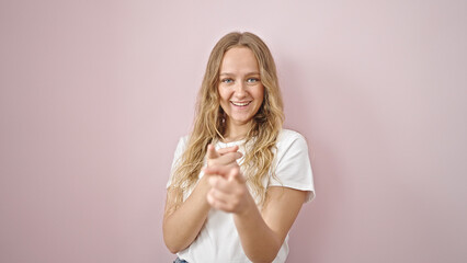 Young blonde woman smiling confident pointing with fingers to the camera over isolated pink background
