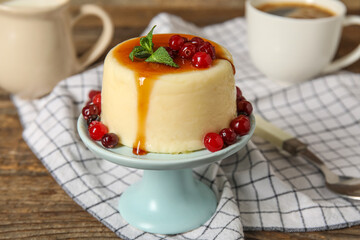 Dessert stand with delicious pudding, mint and cranberries covered by caramel syrup on wooden background