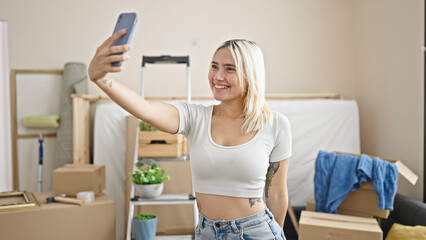 Fototapeta na wymiar Young beautiful hispanic woman make selfie by smartphone at new home