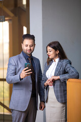 Young Businessman showing some detail in smartphone to his female secretary at office.
