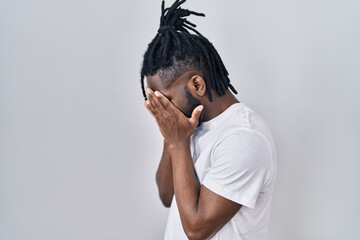 African man with dreadlocks wearing casual t shirt over white background with sad expression...