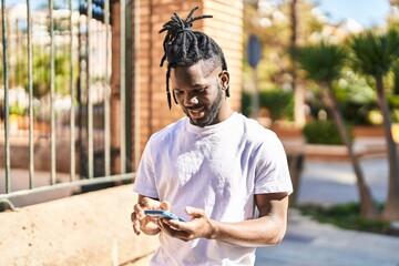 African american woman smiling confident using smartphone at street