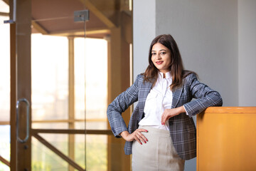 Young and confident corporate woman standing at office.